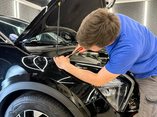 Process of paintless dent repair on car body. The mechanic at the auto shop with tools to repair...