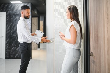 A salesman advises a female customer on the choice of interior doors in a hardware store