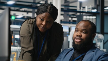 Black team of engineers technicians share ideas in a solar panel factory, reviewing blueprints and...