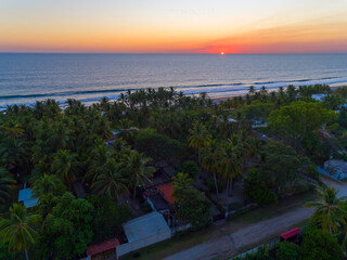 Aerial view of sunset over La Libertad beach in El Salvador, showcasing palm trees and serene waves