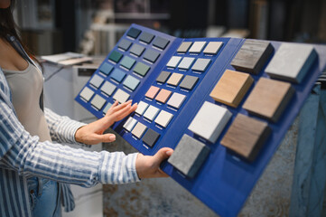 Obraz premium Woman choosing tiles in ceramic and furniture modern shop for her house