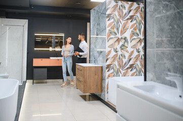 Young woman choosing new bathroom furniture at the plumbing shop with lots of sanitary goods
