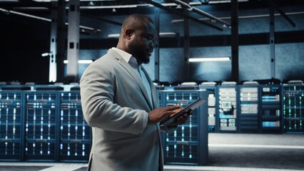 Manager walking in server hub using tablet to find firewall misconfigurations affecting rackmounts...