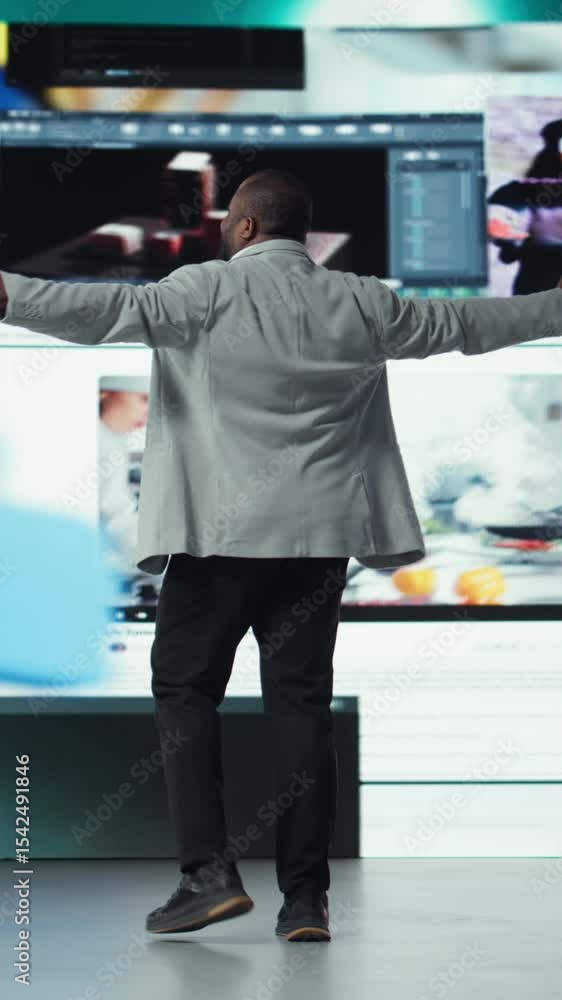 Poster vertical video overjoyed man with open arms facing large digital video wall expressing happiness, be
