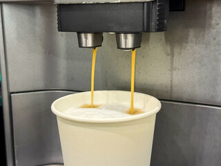 Milk is whipped for cappuccino. Making coffee by coffee machine into paper cup, latte coffee coming...
