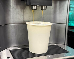 Milk is whipped for cappuccino. Making coffee by coffee machine into paper cup, latte coffee coming...