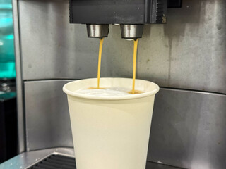 Milk is whipped for cappuccino. Making coffee by coffee machine into paper cup, latte coffee coming...