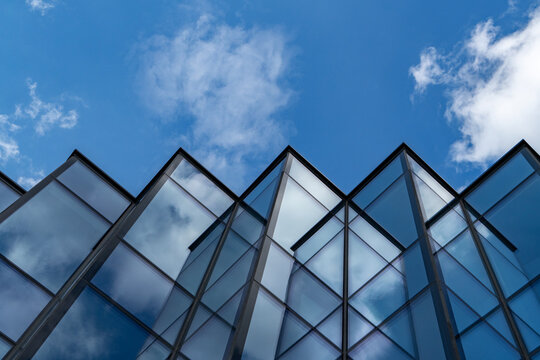 Modern glass building with sky and clouds reflection, abstract urban architecture detail