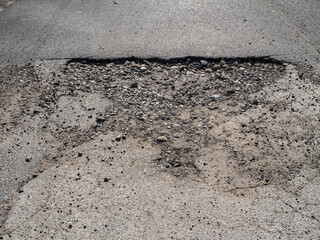 Large pothole in damaged asphalt road, hazard for vehicles and indicator of poor infrastructure maintenance