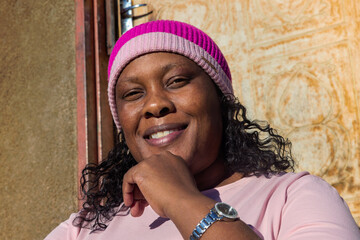 village single african happy woman sited in front of the house , in the yard, overweight wearing...