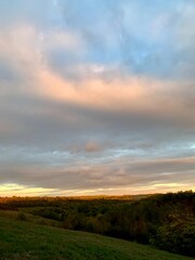 Sunset. Warm sunlight on green hills and tree crowns.