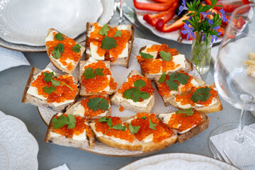 Deliciously plated bread with creamy spreads and bright salmon roe garnished with fresh herbs on a festive dining table with colorful vegetables