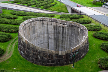 Unique circular concrete structure surrounded by manicured grass in a modern urban setting captured during daylight hours with clear skies