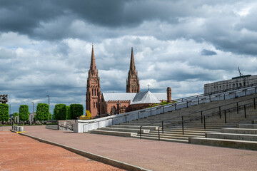 Cathedral with twin spires stands amidst dramatic cloudscape in a quiet Albany park