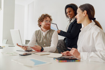 A diverse and inclusive team engages in a highly productive business meeting utilizing their digital devices