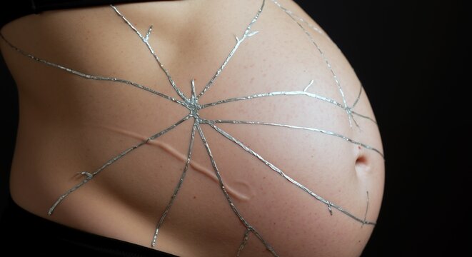 Pregnant belly silver tape spider web pattern artistic maternity photography. Creative pregnancy body art conceptual portrait. Motherhood expecting concept