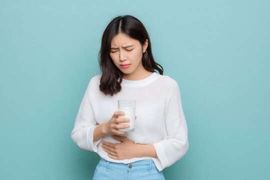 Asian woman distressed with stomach pain after drinking milk indicating lactose intolerance and calcium issues