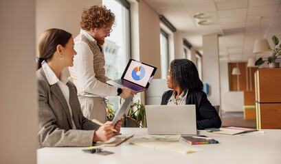 Professionals gather to discuss data insights using tech tools in an office, fostering...