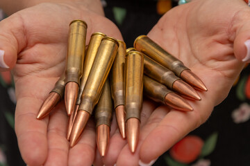 A woman's palms with firearm cartridges is a symbol of threat, military conflict or hunting.