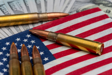 Live ammunition rests on the American flag, with $100 notes.
