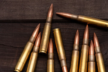 Close-up of various calibres of ammunition lying on a rough wooden board. Suitable for topics related to hunting, shooting or military affairs.