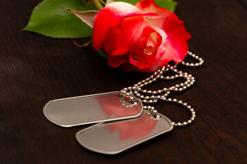 rose with metal identification tags on dark wood. Ideas of patriotism, courage, duty and eternal memory, military conflicts, veterans and history.