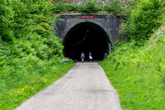 Tourists walking dogs towards Chee Tor Tunnel entrance in Peak District National Park - Powered by Adobe