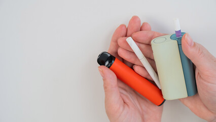 Woman holding regular, electronic cigarette and disposable vape on white background. Tobacco...
