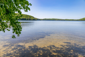 A serene view of the calming waters of Solitaire Lake surrounded by lush greenery in Huntsville, Muskoka, Ontario.