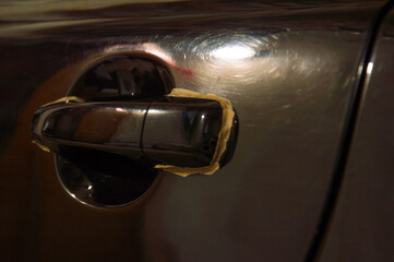 A car door handle is being polished with precision, highlighting the meticulous detailing process...