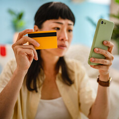 japanese woman hold a credit card and has an anxious facial expression