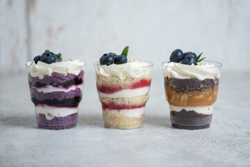 3 flavors trifles: lavender-blueberry, strawberry-mascarpone, peanut-caramel-vanilla. Dessert decorated with berries.