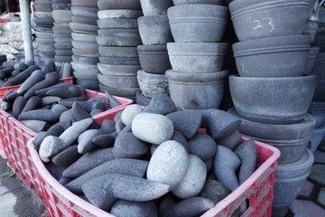 Piles of natural stone mortars and pestles sold by traditional sellers.