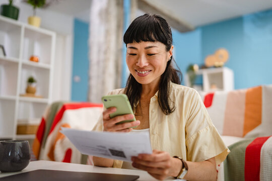 Japanese mature woman use mobile phone to pay bills,