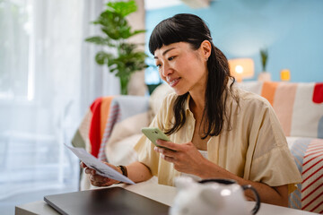 Japanese mature woman use mobile phone to pay bills,