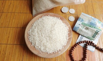 The concept of zakat fitrah. Rice, prayer beads, and money are placed on the table. Religious donations in Islam for the poor during the month of Ramadan.