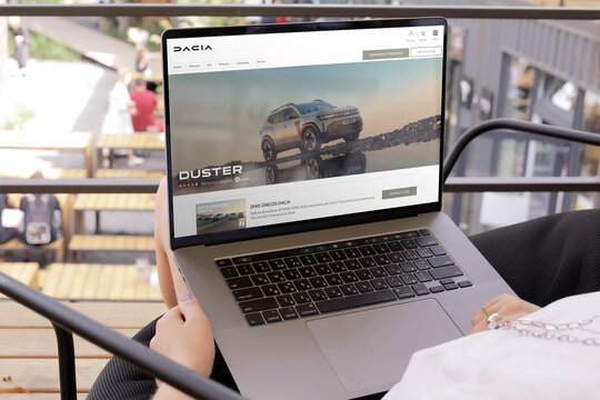 Woman using laptop showing dacia duster suv website in a terrace
