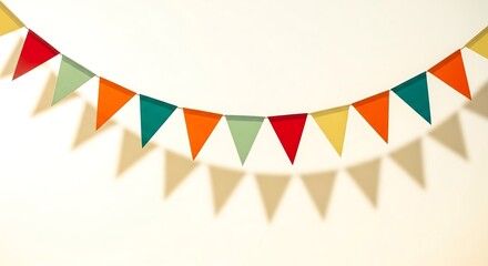 Fototapeta premium Colorful bunting hanging against a light wall, casting a shadow. Party flags in red, orange, green, and yellow create a festive, simple decoration.