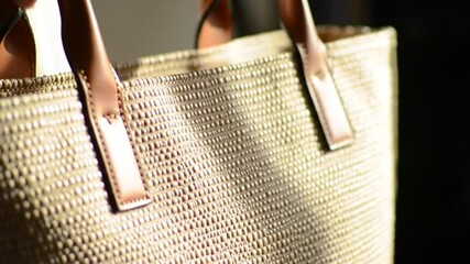 Close up shot of a woven tote bag with brown leather handles in soft natural lighting indoors - Powered by Adobe