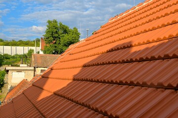 Newly covered roof. New roof covering with red clay tiles. Industrially manufactured tiles on the new roofing. Concept of construction, building work, and renovations on the house
