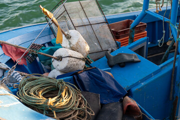 Fishing boat showcases its vibrant blue interior cluttered with assorted gear, including ropes,...