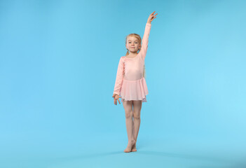 Obraz premium Cute little girl dancing on light blue background