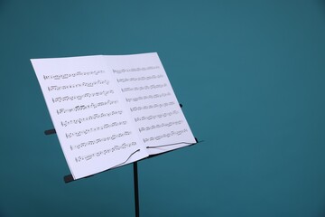 Note stand with music sheets on light blue background, space for text