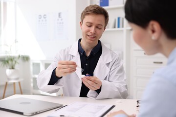 Fototapeta premium Ophthalmologist consulting woman at white table in clinic