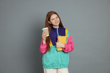 Teenage girl with drink on grey background