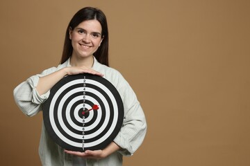 Targeting. Smiling woman with dart board and arrow on beige background. Space for text