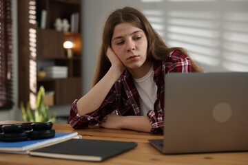 Stressed teenage girl studying at desk indoors