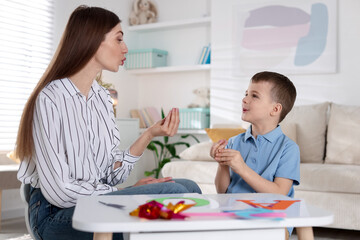 Speech therapist working with little boy indoors