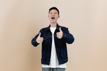 young asian man giving thumbs up in studio background