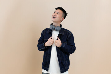 excited young asian model hearing with headphone in studio background